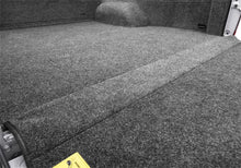 Load image into Gallery viewer, Close-up of the BedRug liner with a yellow label inside a truck bed