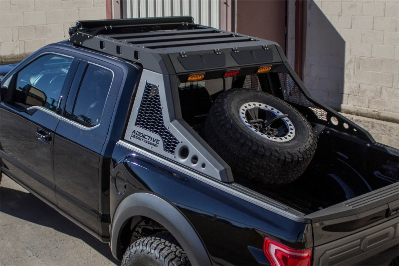 Ford F-150 Raptor's truck bed featuring the HoneyBadger tire rack by Addictive Desert Designs