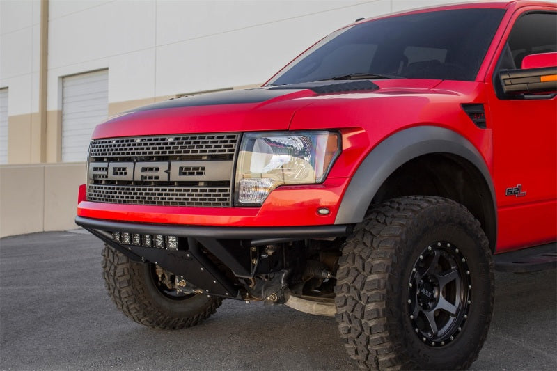 Red Ford F-150 Raptor with ADD PRO bumper parked outside a building